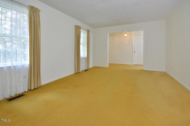 unfurnished room with visible vents, baseboards, and light colored carpet