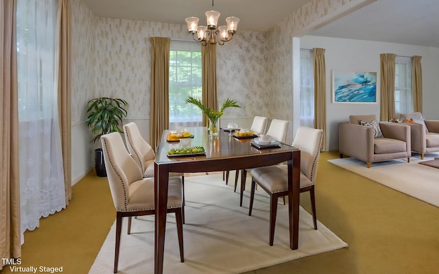 carpeted dining space featuring wallpapered walls and a chandelier