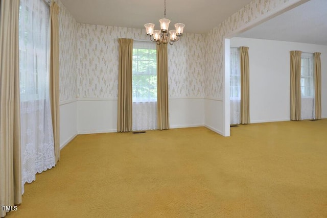 carpeted spare room with baseboards, wainscoting, a chandelier, and wallpapered walls