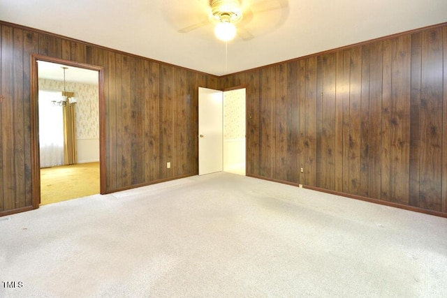 empty room with carpet floors, a ceiling fan, and wood walls