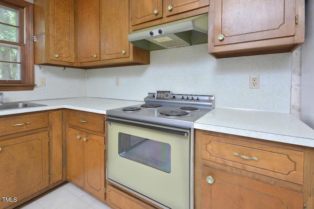 kitchen featuring brown cabinetry, electric stove, and under cabinet range hood