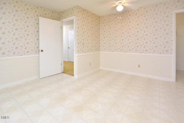 spare room with a wainscoted wall, ceiling fan, and wallpapered walls