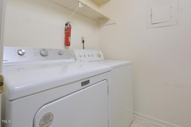 washroom with laundry area, electric panel, washing machine and clothes dryer, baseboards, and light tile patterned flooring