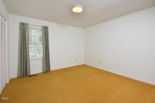 empty room featuring baseboards, light carpet, and visible vents