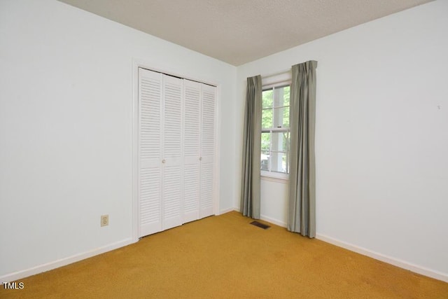 unfurnished bedroom with baseboards, light carpet, a closet, and visible vents