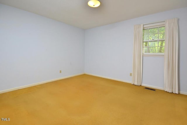 spare room featuring carpet floors, baseboards, and visible vents