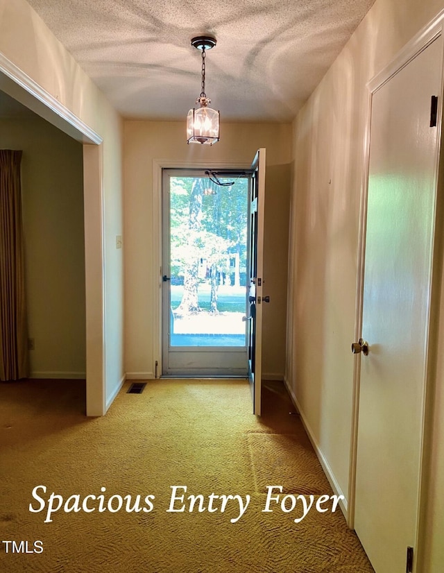 entryway with visible vents, light carpet, baseboards, a textured ceiling, and a notable chandelier