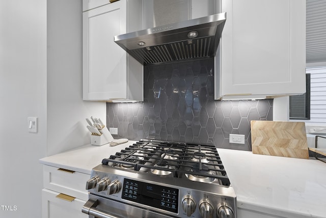 kitchen with range hood, backsplash, stainless steel gas stove, and white cabinets