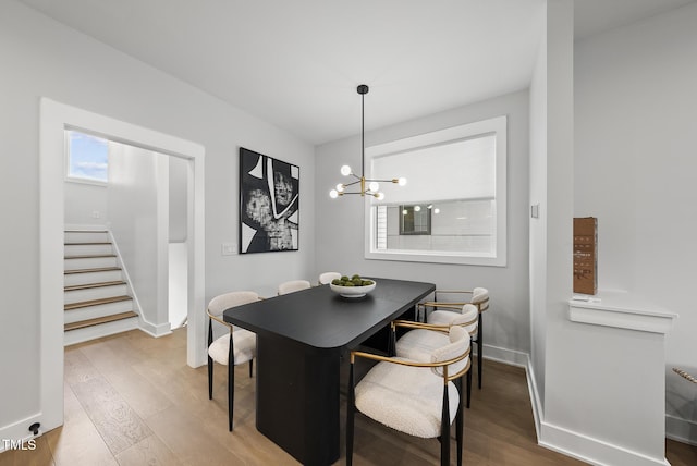 dining room featuring baseboards, stairs, wood finished floors, and a chandelier