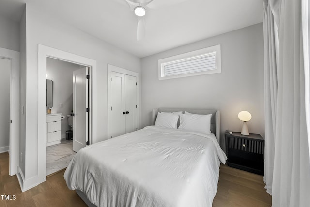 bedroom featuring baseboards, ensuite bathroom, a closet, and wood finished floors