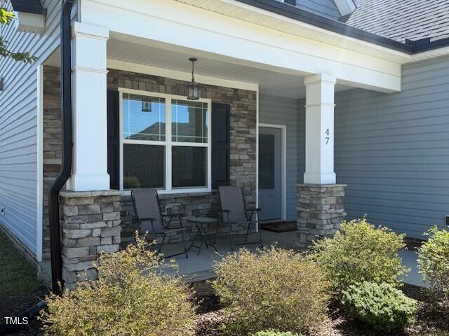 doorway to property featuring covered porch and stone siding