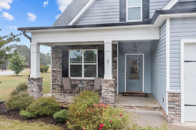 view of exterior entry featuring covered porch and stone siding