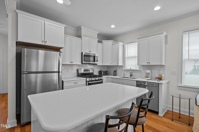 kitchen featuring appliances with stainless steel finishes, a sink, light countertops, white cabinetry, and decorative backsplash