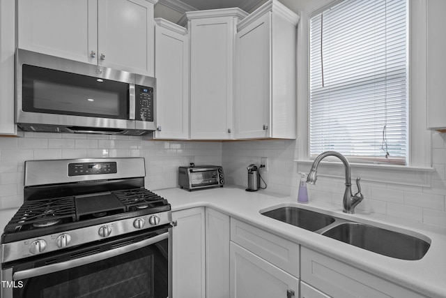 kitchen with white cabinets, a sink, a toaster, stainless steel appliances, and tasteful backsplash