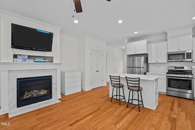kitchen with crown molding, white cabinets, a center island, stainless steel appliances, and recessed lighting