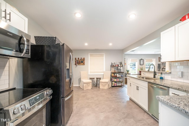553 Isley Rd, Haw River, NC 27258 - kitchen featuring appliances with stainless steel finishes, a sink, light stone counters, decorative backsplash, and white cabinetry