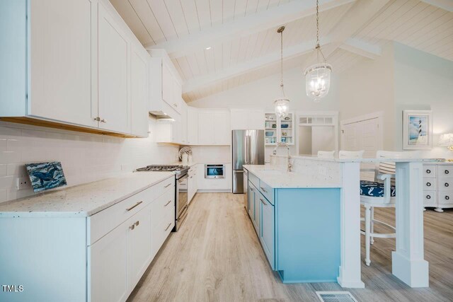 328 Boone St, Chapel Hill, NC 27516 - kitchen with stainless steel appliances, light wood finished floors, a kitchen breakfast bar, white cabinetry, and blue cabinets