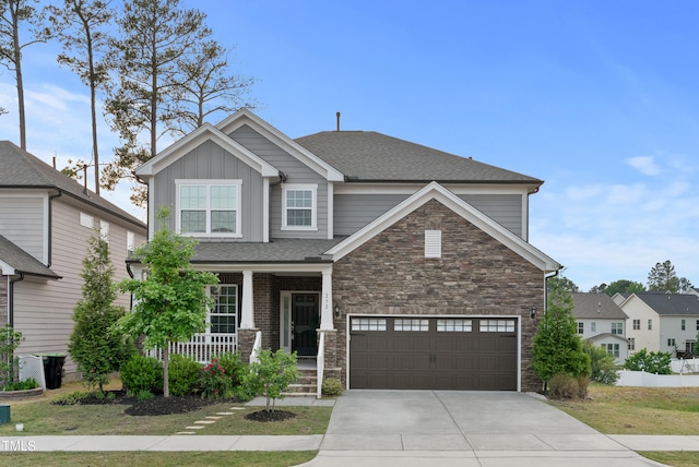 craftsman-style house with covered porch, board and batten siding, driveway, and stone siding