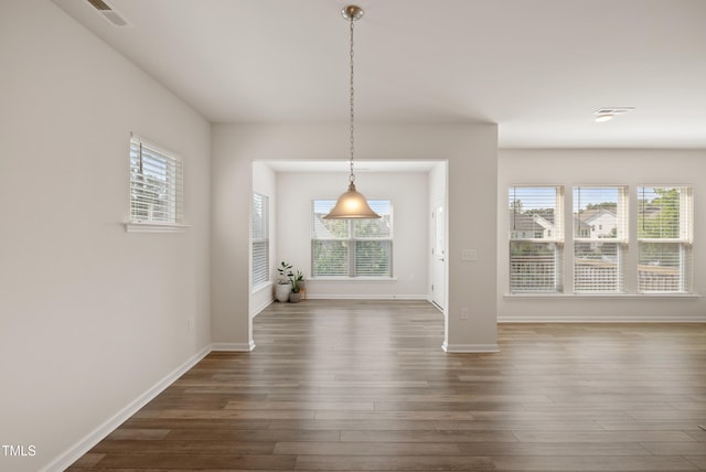 unfurnished dining area with a healthy amount of sunlight, dark wood-style flooring, and visible vents