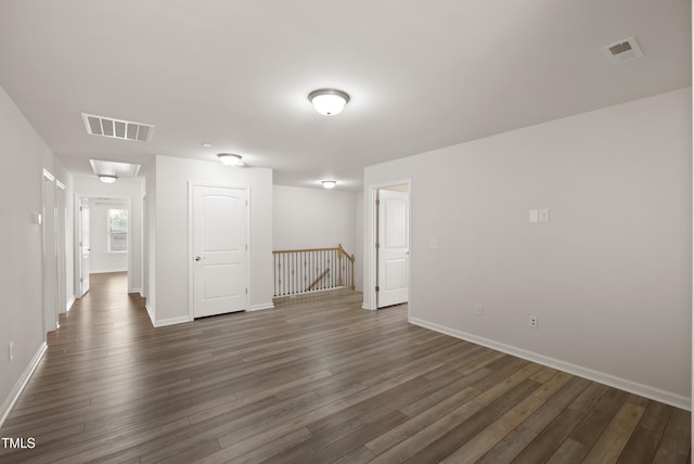 spare room featuring baseboards, dark wood-style floors, and visible vents