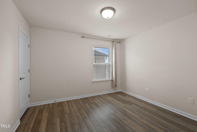 spare room featuring baseboards and dark wood-style floors