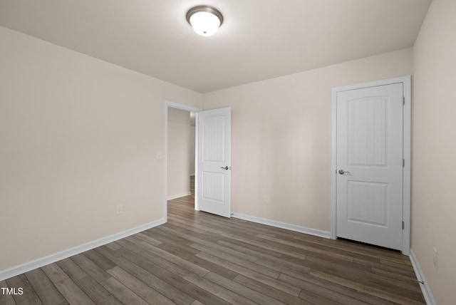 unfurnished room featuring baseboards and dark wood-style floors