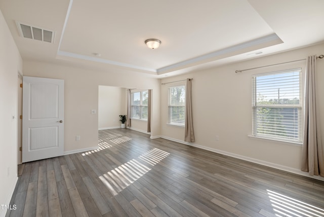 unfurnished room with visible vents, baseboards, a raised ceiling, and wood finished floors