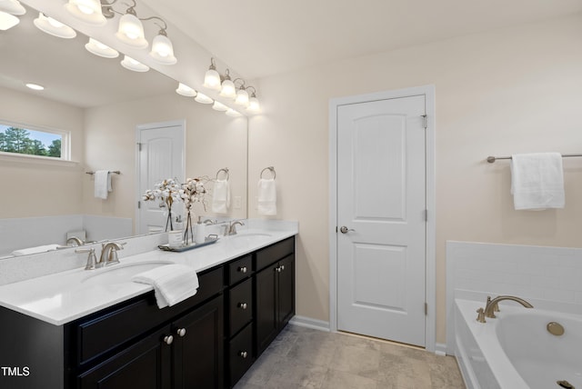full bath with double vanity, baseboards, a sink, and a bath
