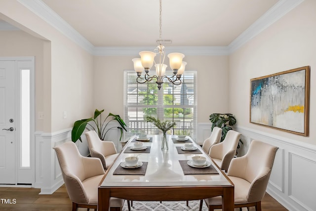 dining area with ornamental molding, wainscoting, wood finished floors, and a notable chandelier