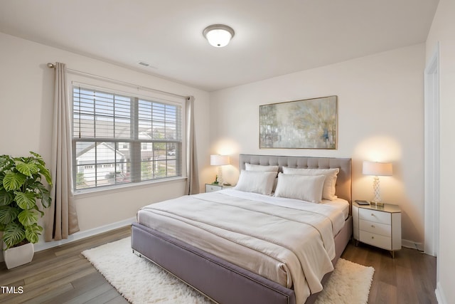 bedroom with baseboards, visible vents, and wood finished floors