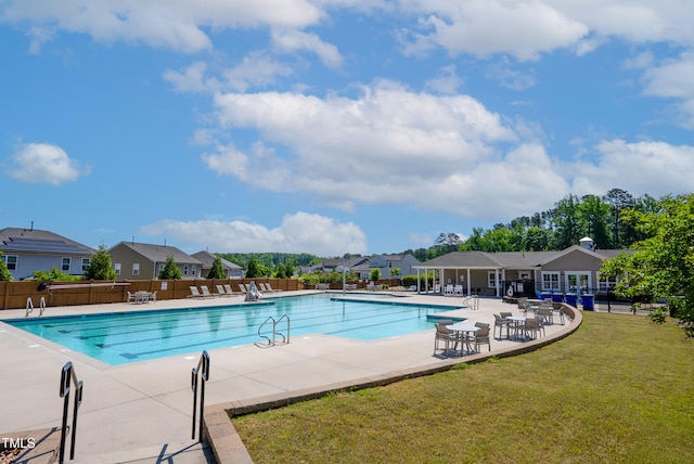 pool featuring a lawn, a patio, fence, and a residential view