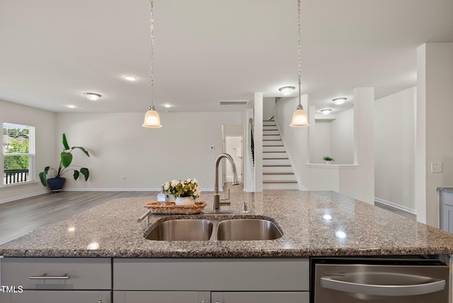 kitchen with visible vents, dishwasher, a sink, light stone counters, and open floor plan