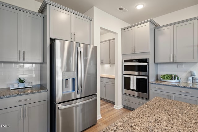 kitchen featuring appliances with stainless steel finishes, gray cabinets, tasteful backsplash, and visible vents