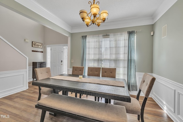 312 Grassy Point Rd, Apex, NC 27502 - dining area featuring a chandelier, light wood finished floors, a wainscoted wall, a decorative wall, and crown molding