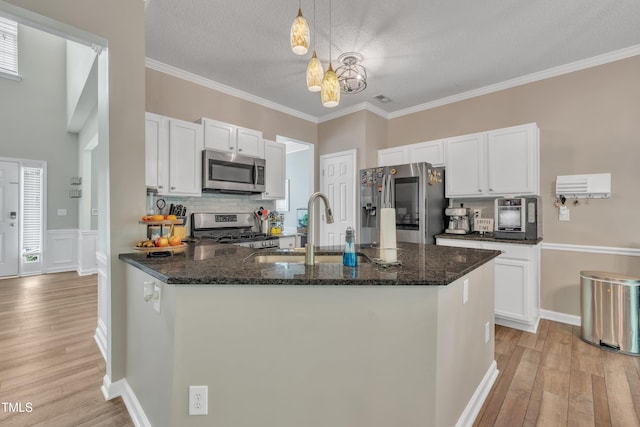 312 Grassy Point Rd, Apex, NC 27502 - kitchen with stainless steel appliances, a sink, light wood-style flooring, white cabinets, and ornamental molding