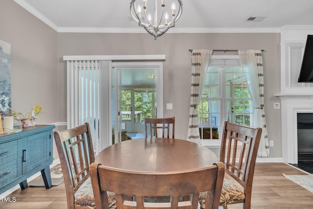 312 Grassy Point Rd, Apex, NC 27502 - dining room featuring light wood-style flooring, a chandelier, ornamental molding, a fireplace with flush hearth, and baseboards
