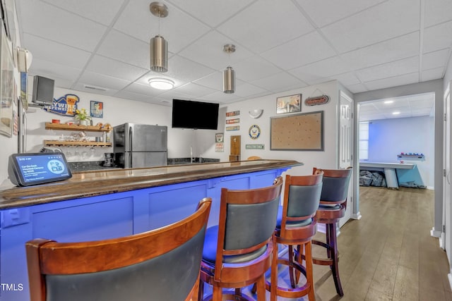 312 Grassy Point Rd, Apex, NC 27502 - indoor bar featuring freestanding refrigerator, a drop ceiling, hanging light fixtures, and wood finished floors