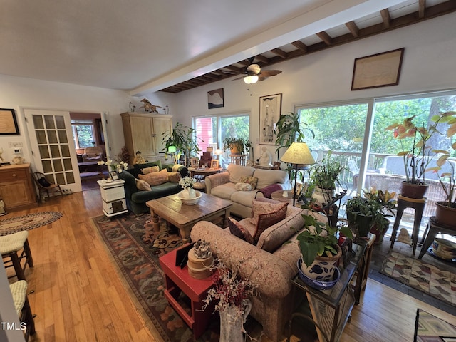 living room featuring a ceiling fan, light wood finished floors, beam ceiling, and a healthy amount of sunlight