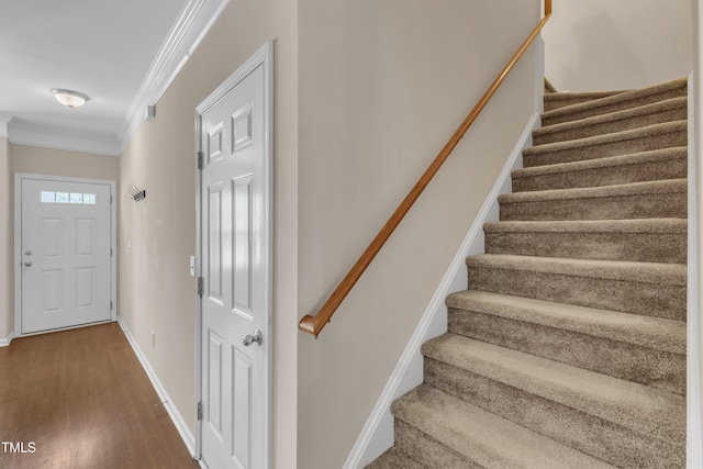 staircase with crown molding, baseboards, and wood finished floors