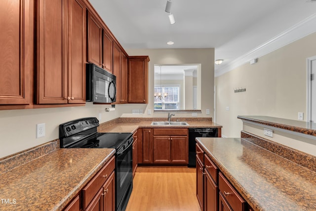 kitchen featuring dark countertops, a sink, black appliances, and light wood-style floors