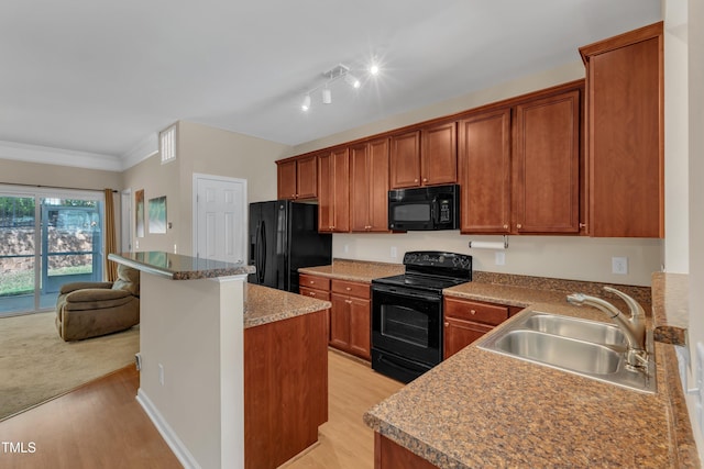 kitchen featuring a sink, brown cabinetry, black appliances, and light wood finished floors
