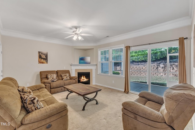 living area with light colored carpet, a ceiling fan, crown molding, and a lit fireplace