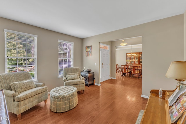 sitting room with wood finished floors, baseboards, and a chandelier