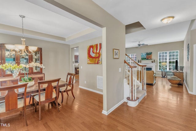 dining room with light wood-style flooring, baseboards, ceiling fan, and a chandelier
