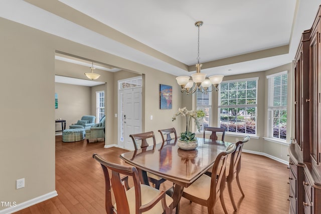 dining room featuring hardwood / wood-style flooring, baseboards, a chandelier, and a tray ceiling