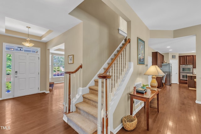 foyer entrance with dark wood finished floors, stairs, baseboards, recessed lighting, and a raised ceiling