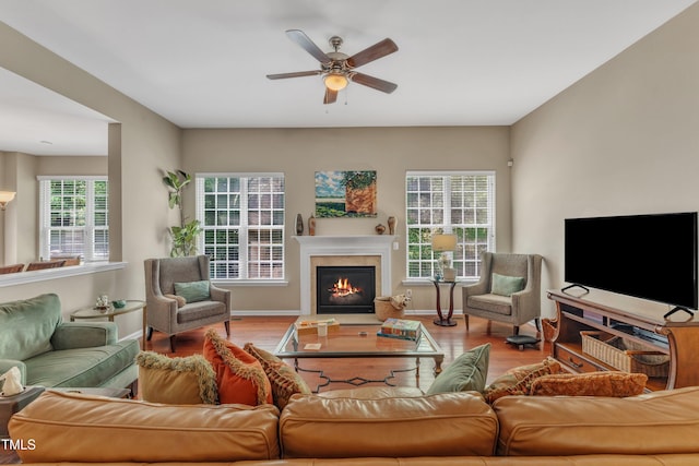 living room with wood finished floors, a fireplace with flush hearth, a ceiling fan, and baseboards