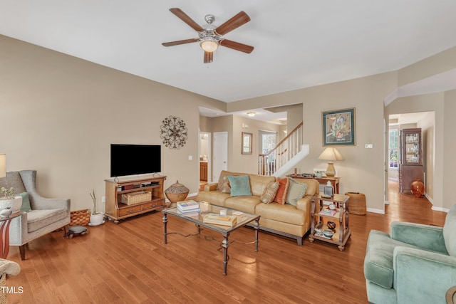 living area featuring ceiling fan, stairway, wood finished floors, and baseboards