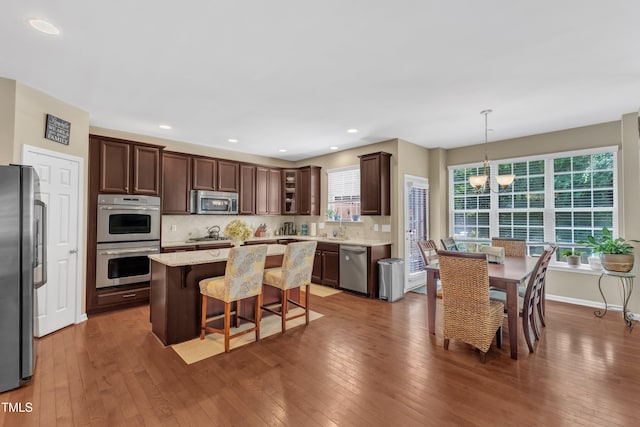 kitchen featuring appliances with stainless steel finishes, a chandelier, hardwood / wood-style flooring, tasteful backsplash, and recessed lighting