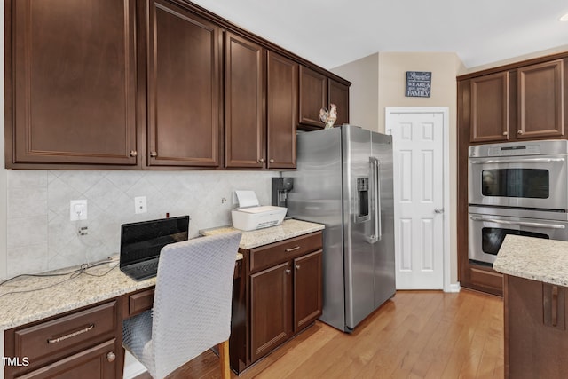 kitchen with appliances with stainless steel finishes, light wood-style floors, tasteful backsplash, light stone countertops, and dark brown cabinets